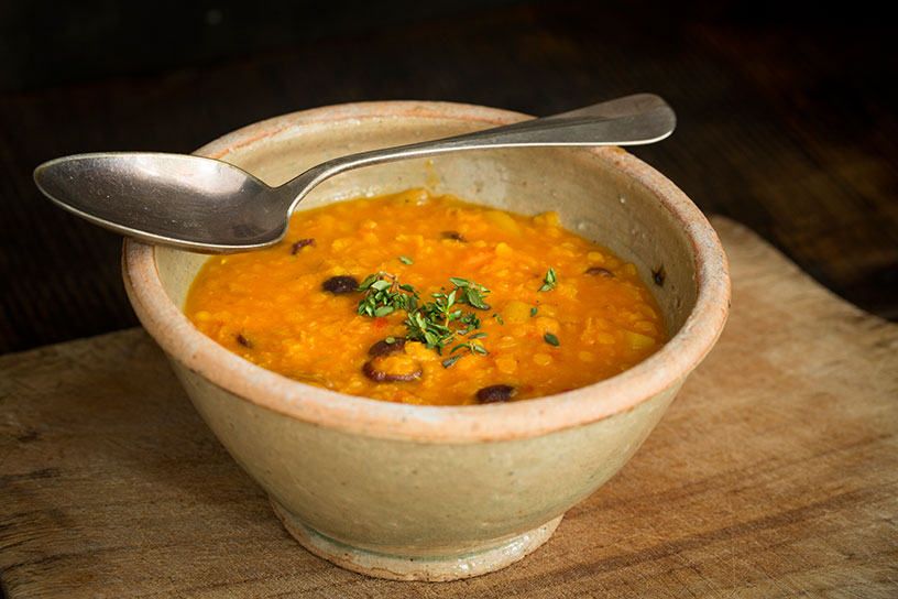 Rode linzensoep in een kom met een lepel